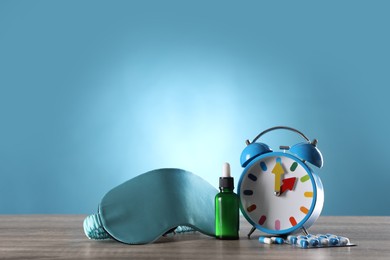 Sleeping mask, alarm clock and insomnia remedies on wooden table