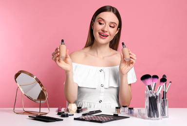 Beauty blogger showing bottles of foundation on pink background