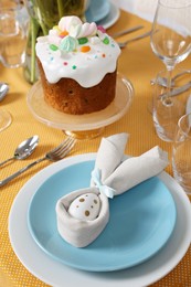 Photo of Festive table setting with painted egg, traditional Easter cake and cutlery