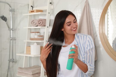 Woman applying dry shampoo onto her hair in bathroom