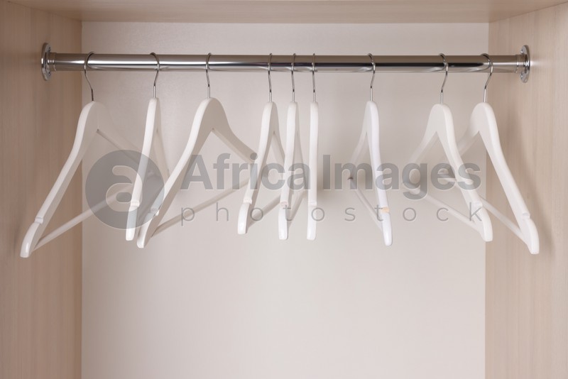 Photo of Set of wooden clothes hangers on wardrobe rail