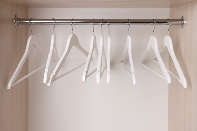 Set of wooden clothes hangers on wardrobe rail