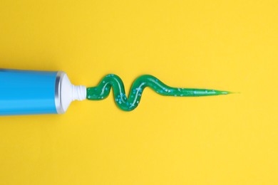 Tube of toothpaste on yellow background, flat lay