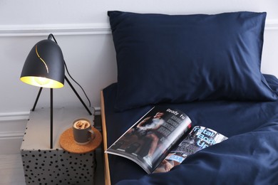 Open magazine on bed with stylish silky linens