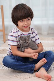 Photo of Cute little boy with kitten on floor at home. Childhood pet