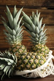 Photo of Bag with fresh juicy pineapples on wooden table, closeup