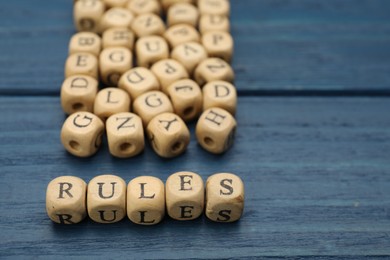 Photo of Word Rules made of cubes with letters on blue wooden table