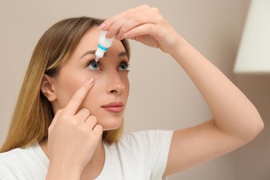 Young woman using eye drops at home