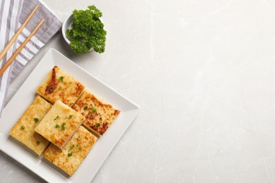 Photo of Delicious turnip cake with parsley served on light table, flat lay. Space for text