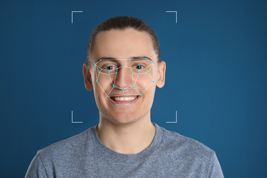 Facial recognition system. Man with scanner frame and digital biometric grid on blue background