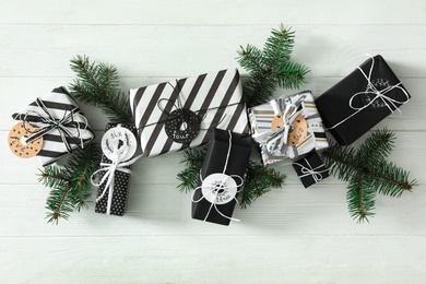 Gifts for Christmas advent calendar and fir branches on white wooden table, flat lay.