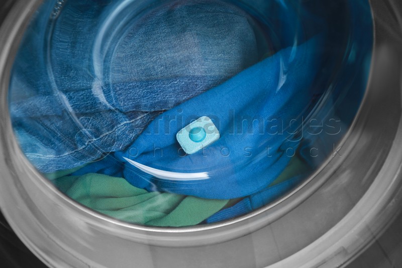 Water softener tablet on clothes in washing machine, closeup
