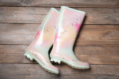 Pair of colorful rubber boots on wooden background, top view