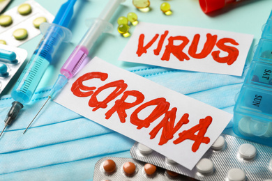 Phrase CORONA VIRUS and medicines on light blue background