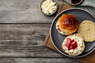 Photo of Freshly baked soda water scones with cranberry jam and butter on wooden table, flat lay. Space for text