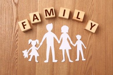 Paper cutout and word Family made of wooden cubes with letters on table, flat lay