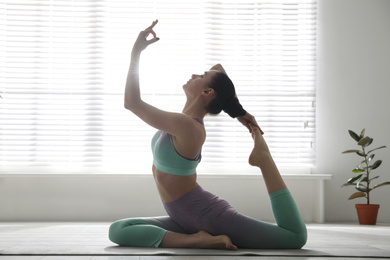 Woman practicing one legged king pigeon asana in yoga studio. Eka pada rajakapotasana pose
