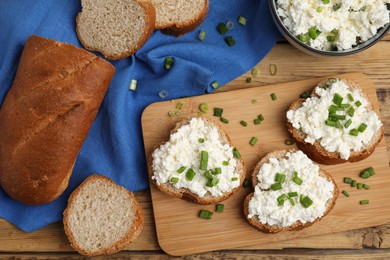 Bread with cottage cheese and green onion on wooden table, flat lay