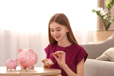 Teen girl with piggy banks and money at home