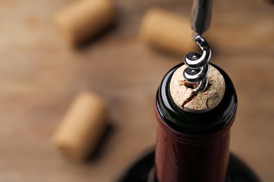 Opening wine bottle with corkscrew on table, closeup. Space for text