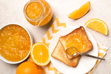 Delicious orange marmalade and toasts on light table, flat lay