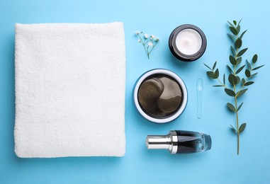Flat lay composition with under eye patches and other cosmetic products on light blue background