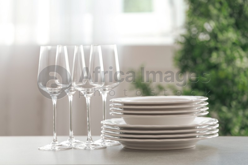 Photo of Set of clean dishes and wineglasses on table indoors