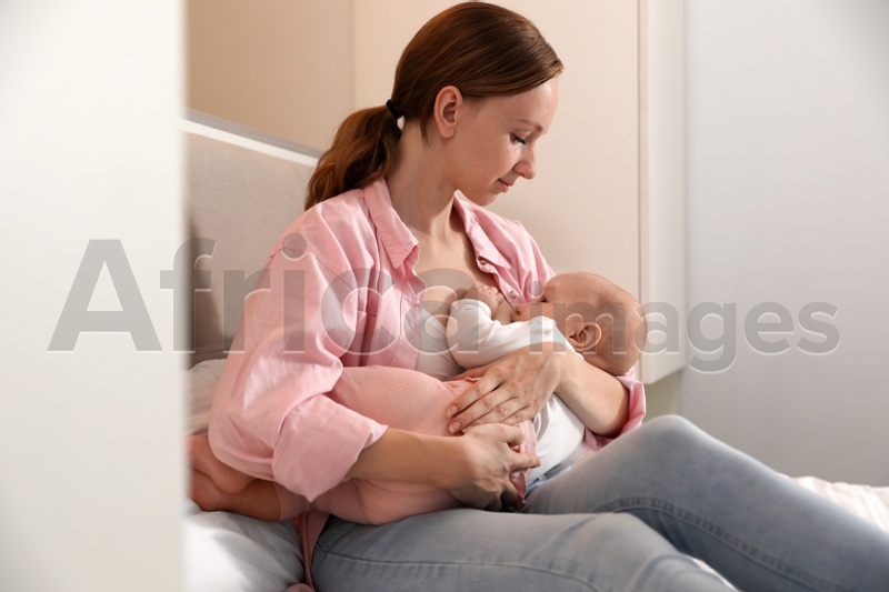 Young woman breast feeding her little baby in bedroom
