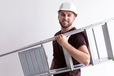 Young working man with ladder on white background