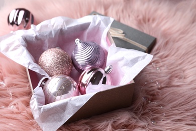 Beautiful Christmas baubles in box on pink faux fur