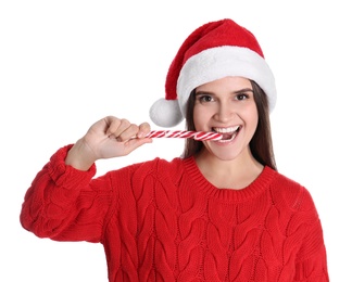 Pretty woman in Santa hat and red sweater eating candy cane on white background