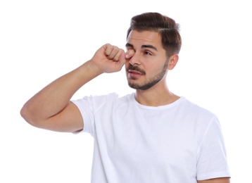 Young man rubbing eye on white background. Annoying itch