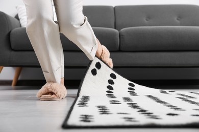 Photo of Woman tripping over carpet at home, closeup
