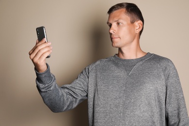 Man unlocking smartphone with facial scanner on beige background. Biometric verification