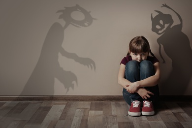 Image of Shadows of monsters on wall and scared little girl in room