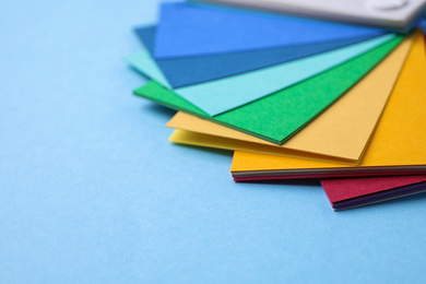 Multicolored paper sheets on light blue background, space for text. Rainbow palette