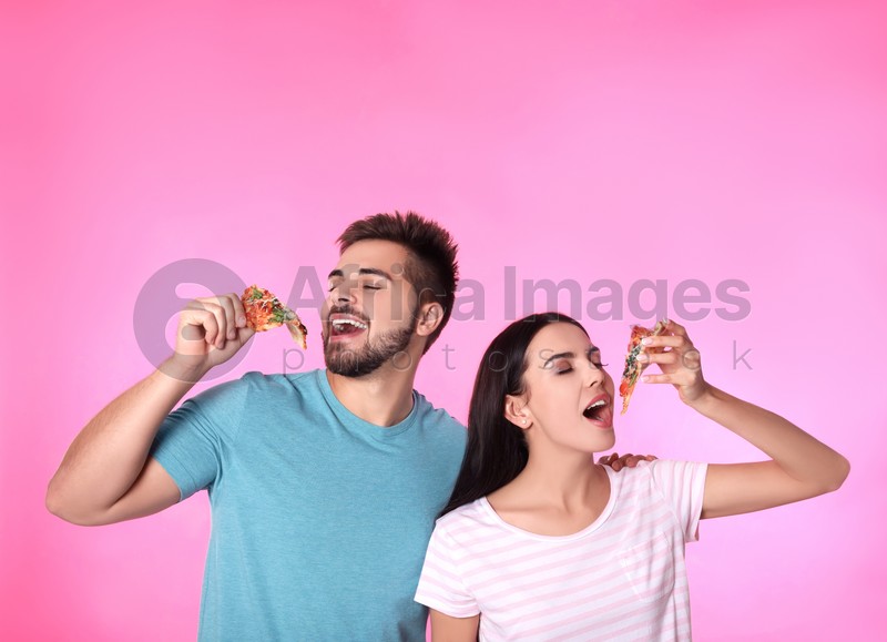 Photo of Happy couple with pizza on pink background