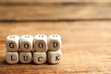Cubes with phrase GOOD LUCK on wooden table, closeup. Space for text