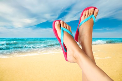 Woman wearing stylish flip flops resting on sandy beach and enjoying beautiful seascape, closeup 