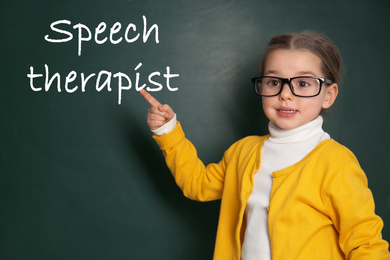 Cute little child near chalkboard and text Speech Therapist 