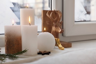 Photo of Beautiful burning candles with Christmas decor on windowsill indoors, space for text