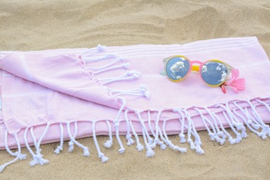 Photo of Blanket with stylish sunglasses and flower on sand outdoors. Beach accessories