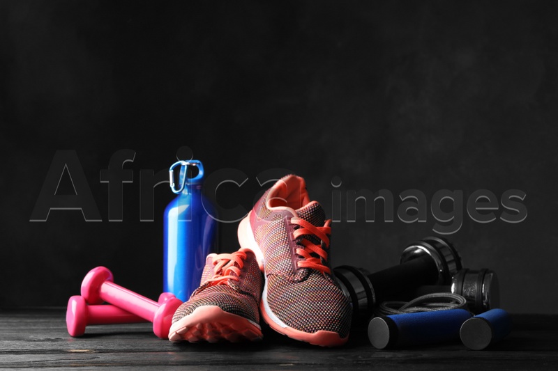 Gym equipment and accessories on wooden floor against dark background