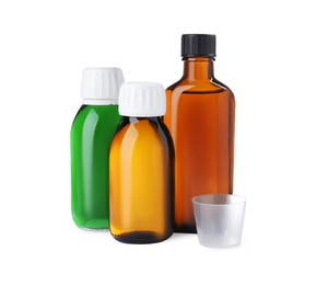 Photo of Bottles of syrups with measuring cup on white background. Cough and cold medicine