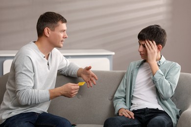 Father talking with his teenage son about contraception at home. Sex education concept