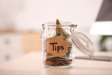 Glass jar with tips on wooden table indoors, closeup