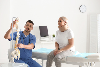 Male orthopedist explaining structure of spine to patient in clinic