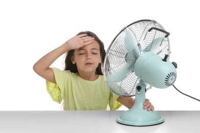 Little girl suffering from heat in front of fan on white background. Summer season