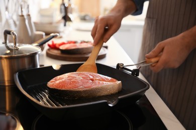 Man cooking fresh salmon steak in frying pan, closeup