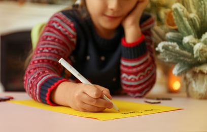Cute child writing letter to Santa Claus at table, closeup. Christmas tradition